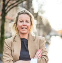 Lachende vrouw in zakelijke jas buiten, sociaal en professioneel, Suyt Sociaal.